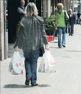  ?? KIM MANRESA ?? Una mujer sale cargada con dos bolsas de productos de Dia