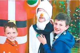  ??  ?? Chris Richards, left, and Will McLean wrap up Frosty the Snowman (Max Richards) at the Tetoora Road Christmas tree party.