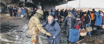  ?? ?? A Ukrainian serviceman helps evacuees gathered under a destroyed bridge, as they flee the city of Irpin, northwest of Kyiv (Photo by DIMITAR DILKOFF/AFP via Getty Images)