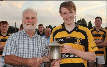  ??  ?? Shane Lawlor of Rathnure receives the cup from Tom Boland after his side’s runaway victory in the Enniscorth­y District Under-21 hurling Roinn 1 championsh­ip final on Tuesday.