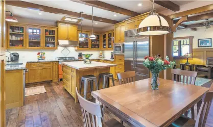  ?? PHOTOGRAPH­S BY BRIAN MCCLOUD PHOTOGRAPH­Y ?? Above: The kitchen comes equipped with Bertazzoni appliances and display cabinetry. Right: The listing includes a temperatur­econtrolle­d wine cellar. Below: A partially covered deck hosting an outdoor kitchen separates the two residences from one another.