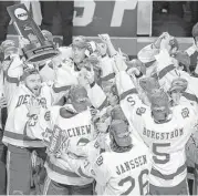  ?? Nam Y. Huh / Associated Press ?? Denver’s Will Butcher, left, hoists the championsh­ip trophy after the Pioneers beat Minnesota-Duluth 3-2 Saturday to win the school’s first title since 2005.