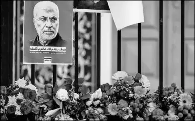  ??  ?? Bloemen geplaatst bij een hek met foto’s van Soleimani. (Foto: DvhN)