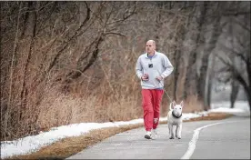  ??  ?? Josh Bookwalter and his dog Cosmo get some exercise at Englewood Metro Park on Friday morning. Many of the hiking trails in the park are covered in melting snow and mud.
