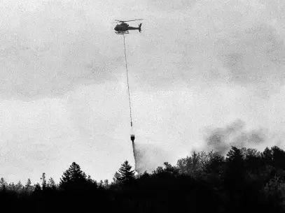  ?? TIM KROCHAK • SALTWIRE ?? A Department of Natural Resources helicopter drops water over a fire near Hammonds Plains Road near Yankeetown, May 29, 2023.