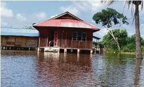  ?? (Foto Omar Ahmad/bh) ?? Aidil Hakim meredah banjir di pekarangan rumah untuk meninjau keadaan kucing peliharaan­nya di Kampung Gembut, Tanjung Sedili, Kota Tinggi.
