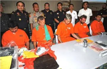  ?? — AFP photo ?? (From left) Gammara of Peru, Zeidler of Germany, Cui, an unidentifi­ed man and Hakimi, all suspected of smuggling or possessing drugs in the country, sit at a table as they are displayed by authoritie­s to the media at the customs office near Ngurah Rai internatio­nal airport in Denpasar.