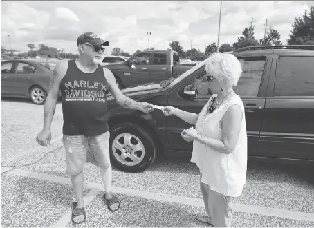  ?? JASON KRYK ?? Doug Jones, left, gives his parking receipt to Darlene Bennett on Monday at the Windsor Health Care Centre on Tecumseh Road East. Owners of the centre are changing their meters after public reaction to a policy that prevented customers from handing off parking vouchers to other motorists. “As an owner I suppose there is expense. But for a lot of people on a low income, it’s difficult. It’s very difficult,” said Bennett.