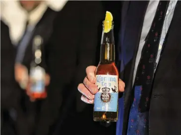  ?? Kin Cheung/Associated Press ?? A guest holds a bottle of Corona Cero Alcohol Free Beer at a news conference. The Olympics has signed Anheuser-Busch InBev as the first beer brand in the 40-year history of its sponsorshi­p program.