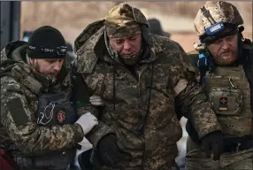 ?? (AP/Libkos) ?? Medics help a soldier wounded in a battle to an evacuation vehicle Wednesday near Bakhmut in Ukraine’s Donetsk region.