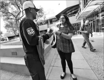  ?? ASSOCIATED PRESS PHOTOS ?? PHOENIX FIREFIGHTE­R JUAN RODRIGUEZ HANDS OUT A COOLING NECKERCHIE­F (above and below) to morning commuter Arielle Thomas early Monday in downtown Phoenix. Parts of Arizona and the Southwest are bracing for the hottest weather of the year with highs this...