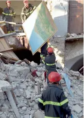  ?? — AFP ?? Firefighte­rs remove a painting from the rubble of a damaged house in San Lorenzo, near the Italian village of Amatrice, on Saturday.