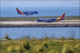  ?? RAY CHAVEZ — STAFF PHOTOGRAPH­ER ?? A Southwest airplane arrives as another gets ready to depart from the Oakland Internatio­nal Airport, seen from San Leandro on Thursday.