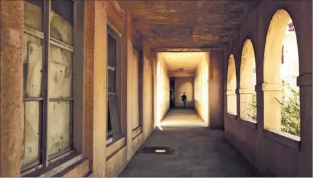  ?? Photog raphs by Genaro Molina
Los Angeles Times ?? A WOMAN walks through a corridor that leads to a vacant building on the VA campus. Instead of renovating old buildings to accommodat­e veterans, the VA has embarked on a spree of new constructi­on, the report by the National Trust for Historic...