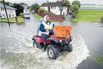  ?? Photos: MAARTEN HOLL/FAIRFAX NZ ?? Biker’s luck: Jaymie Baker ferries his sister Ariel Baker out of their flooded home in Pukaki Grove, Waitangiru­a.