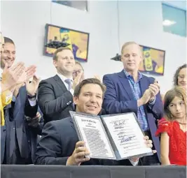  ?? CHRIS O’MEARA/AP ?? Gov. Ron DeSantis holds up a signed bill on vaccines and mask mandates during a news conference on Nov. 18, in Brandon.