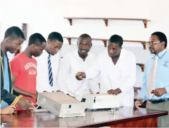  ??  ?? A teacher (right) observes as Lower Six Physics pupils work on an experiment in the school’s laboratory yesterday