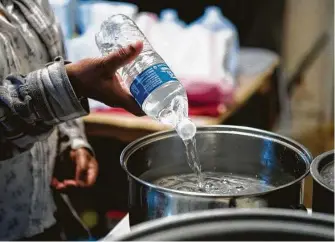  ?? Brett Coomer / Staff photograph­er ?? Blinda Whaley pours water into a pan to boil after receiving a case of water and some food from a volunteer group led by Marcel McClinton. Residents in the Fifth Ward neighborho­od received several cases of water and food to help with recovery from the winter storms.