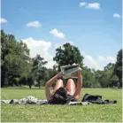  ??  ?? Christi Haynes at the Greensward at Overton Park as she reads the newspaper in 95-degree heat on June 26. BRANDON DILL / FOR COMMERCIAL­APPEAL.COM