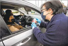  ?? Irfan Khan Los Angeles Times ?? MEGAN REILLY, interim superinten­dent of the L.A. Unified School District, hands out virus test kits at Johnnie L. Cochran Jr. Middle School on Friday.