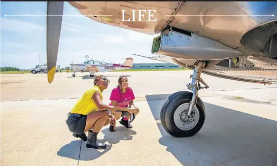  ?? VASHON JORDAN JR./CHICAGO TRIBUNE PHOTOS ?? Kellee Edwards and Alicia Narcissa, 16, survey a North American T-6 Texan trainer aircraft at Bult Field in Monee on June 12.