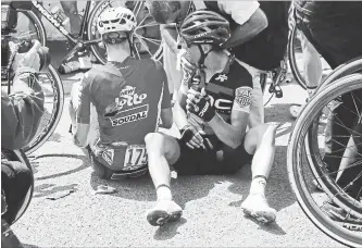  ?? CHRISTOPHE ENA THE ASSOCIATED PRESS ?? Australia’s Richie Porte, right, receives medical attention as he sits on the road with Belgium’s Jens Keukeleire, centre, after crashing during the ninth stage of the Tour de France on Sunday. Porte quit the race.