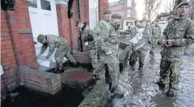  ??  ?? > Members of the armed forces help distribute sandbags to residents following flooding in Carlisle