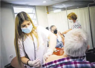  ?? CHUS MARCHADOR ?? Varias enfermeras vacunan a dos zaragozano­s contra el covid, en el centro de salud Actur Oeste.