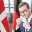  ?? — Reuters ?? Poland’s Prime Minister Mateusz Morawiecki adjusts his mask as he attends an EU leaders summit in Brussels, on Thursday.