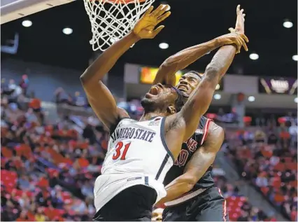  ?? K.C. ALFRED U-T ?? Aztecs’ Nathan Mensah, who had seven points, nine rebounds and a block, is fouled by Troy’s Zay Williams at Viejas Arena.