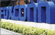  ??  ?? In this file photo, a worker looks out through the logo at the entrance of the Foxconn complex in the southern Chinese city of Shenzhen. Taiwanese electronic­s maker Foxconn’s plan to build a display panel factory in the US has sparked a flurry of...