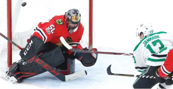  ??  ?? The Stars’ Mattias Janmark scores the game- winning goal against Blackhawks goaltender Corey Crawford in overtime Thursday at the United Center. | JIM YOUNG/ AP