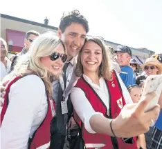  ?? JEFF BASSETT/THE CANADIAN PRESS ?? Prime Minister Justin Trudeau poses for a selfie with Canadian Red Cross workers at event stop in Revelstoke, B.C., on Saturday.