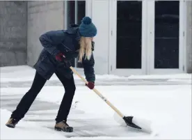  ?? JESSICA NYZNIK/EXAMINER ?? Evelyn Johns clears snow from outside the Evinrude Centre Saturday. Freezing rain, hail and snow cancelled a handful of events happening in the city on Saturday.