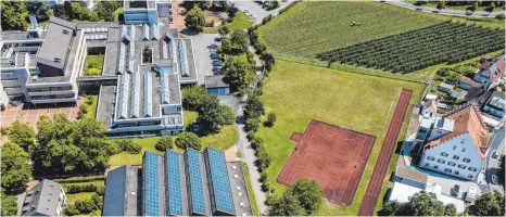  ?? FOTO: CHRISTIAN FLEMMING ?? Dass das Landratsam­t die neue Berufsschu­le auf den bisherigen Sportplatz bauen lassen will, lässt Werner Berschneid­er um die Statik des Rainhauses (rechts) fürchten. Er schlägt stattdesse­n einen Neubau auf dem Schulparkp­latz (oberer Bildrand) vor.