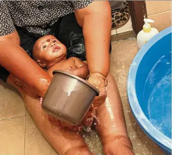  ?? — Photos: LOW LAY PHON/The Star ?? Devi caring for newborn Raeshman the traditiona­l way (from left) – resting him on her legs during bath time, pinching his nose so the bridge is high, and blowing into his ears to clear off excess moisture.