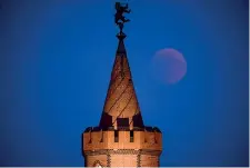  ??  ?? Dall’alto: la Luna color porpora dietro il Colosseo a Roma (Ap); l’eclissi a Berlino sulle torri del ponte Oberbaum (Epa); la Luna eclissata a metà al Cairo (Reuters); si osserva lo spettacolo a Taiwan (Getty Images)