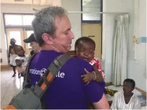  ??  ?? DR. OMRI EMODI cradles a tiny tot in Ghana.