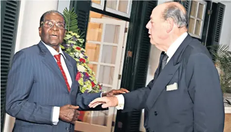  ??  ?? Robert Mugabe greets Sir Nicholas Soames outside the State House earlier this week, above; and Mr Mugabe pictured with Sir Nicholas’ father, Lord Soames, in Eighties’ Rhodesia