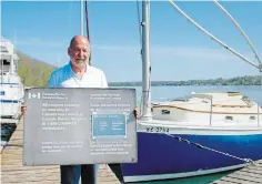  ?? ZAHRAA HMOOD TORSTAR ?? Robert Ciupa, from Smuggler’s Cove Boat Club in Niagara-onthe-Lake, holds the small vessel reportings site sign the club had posted at the marina prior to the pandemic, for boaters crossing the Canada-U.S. border.