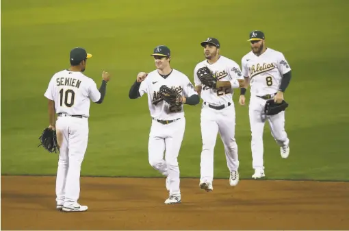  ?? Ezra Shaw / Getty Images ?? Marcus Semien (left) congratula­tes his playoffbou­nd teammates Mark Canha, Ramon Laureano and Robbie Grossman.