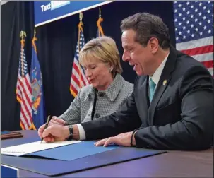  ?? The Associated Press ?? PAVING THE WAY: Former Secretary of State Hillary Clinton joins Gov. Andrew Cuomo for a ceremonial bill signing of the state’s new scholarshi­p for poor and middle-class students Wednesday at LaGuardia Community College in the Queens borough of New York.