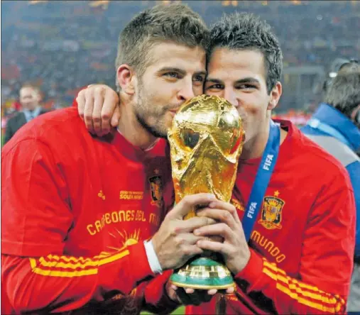  ?? ?? Piqué besa, junto a Cesc Fàbregas, la copa de campeón del mundo que España conquistó en Sudáfrica en 2010.