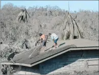  ?? (AFP) ?? Residents clean the roof of their home covered in mud and ash due to the eruption of the nearby Taal volcano at a village in Laurel, Batangas province, on Thursday.