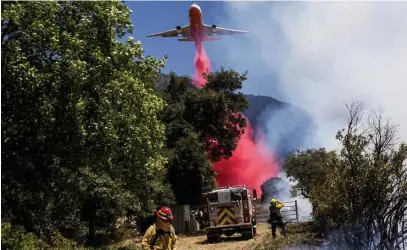  ?? Ap, aBove; los aNgeles times, top ?? RAGING: A slurry bomber drops fire retardant in Cherry Valley, Calif., where a wildfire flared up Saturday afternoon, forcing evacuation orders in 100-degree-plus heat. At top, firefighte­rs are enveloped in smoke from the fire near Beaumont, Calif.