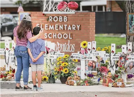  ?? Kin Man Hui/ San Antonio Express- News ?? A mother and son pay a visit to the memorial at Robb Elementary in Uvalde, Texas, on the first anniversar­y of the attack that killed 19 students and two teachers. There were few public observance­s to mark the event.