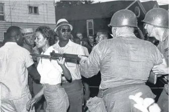  ?? AP ?? Gloria Richardson, head of the Cambridge Nonviolent Action Committee, pushes a National Guardsman’s bayonet aside as she moves among a crowd of African Americans to convince them to disperse in Cambridge, Maryland, on July 21, 1963.