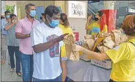  ??  ?? Migrant workers line up ItsRaining­Raincoats.
to receive
gift bags from volunteers of