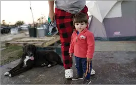  ?? PHOTOS BY GERALD HERBERT — THE ASSOCIATED PRESS ?? Katelyn Smith stands with her 1-year-old son Ricky Trahan III as their family lives in a camper and tents where their home was destroyed in Lake Charles, La., on Dec. 4.