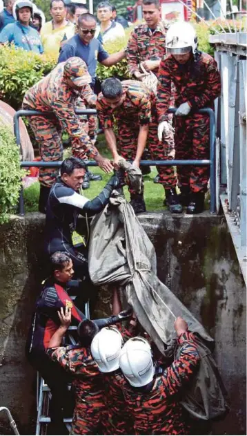  ?? FOTO: ZULAIKHA ZAINUZMAN ?? ANGGOTA bomba dan penyelamat mengusung mayat Lim yang lemas selepas terjatuh dalam longkang ketika banjir kilat di Jalan Sungai Ara, Bayan Lepas.